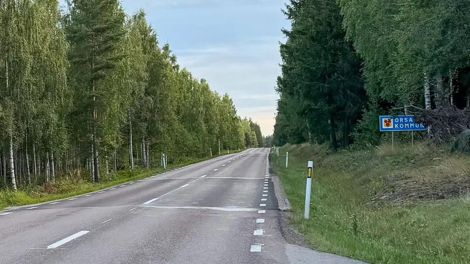 E45 norr ut genom byn Vattnäs vid kommungränsen till Orsa, med skog på båda sidor av vägen. Bild.