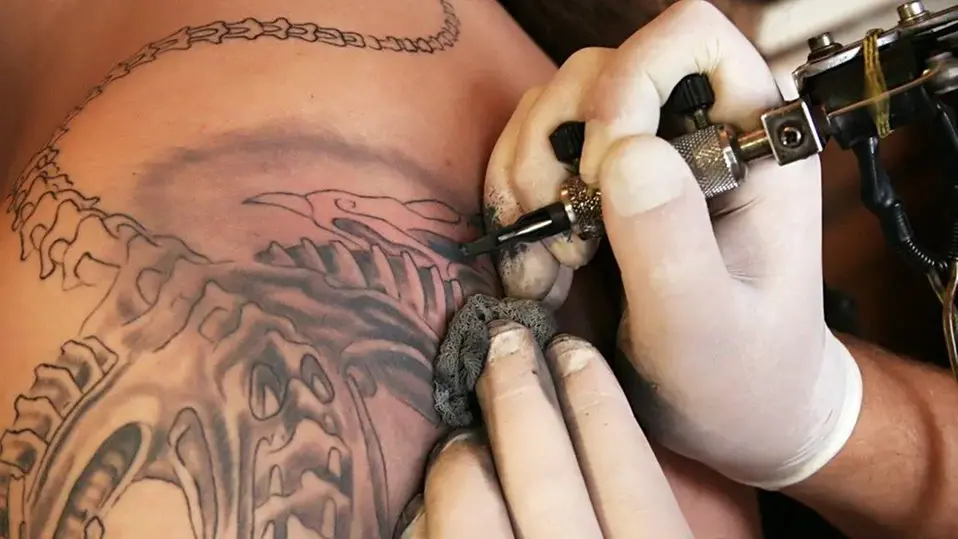 Händer som tatuerar en tatuering